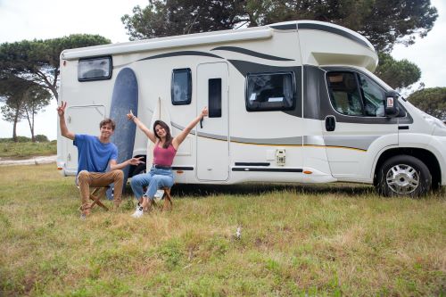 A couple in front of an rv camper trailer.